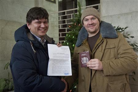 Greenpeace International activist Anthony Perrett (R) from Britain poses with his lawyer Sergey Golubok, who holds papers certifying the termination of prosecution, after he became the first of the 30 Greenpeace Arctic activists to have the criminal case against him dropped, in Saint Petersburg, December 24, 2013, in this handout image courtesy of Greenpeace. REUTERS/Dmitri Sharomov