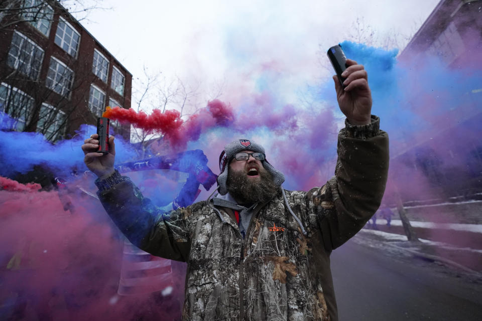 Scott Spencer holds colorful flares as he and a group of United States men's national soccer team supporters march to Lower.com Field ahead of a FIFA World Cup qualifying soccer match against El Salvador, Thursday, Jan. 27, 2022, in Columbus, Ohio. (AP Photo/Julio Cortez)