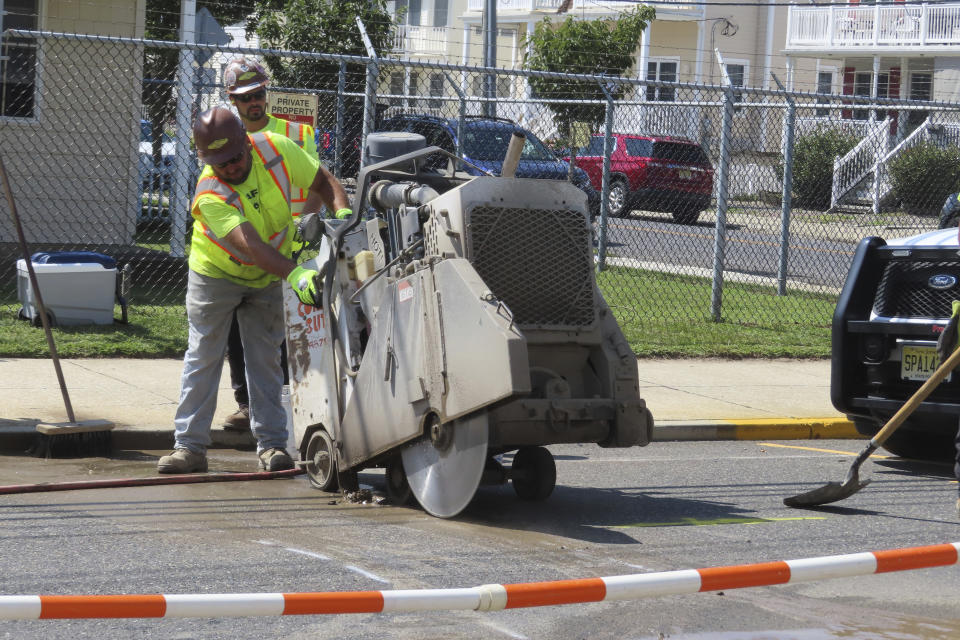 A worker uses an industrial cutting machine to open a section of the street in Ocean City, N.J. on Sept. 12, 2023, at the start of land-based probing along the right-of-way where a power cable for New Jersey's first offshore wind farm is proposed to run. Several protestors were arrested trying to block the work for the project being done by Danish wind energy company Orsted. (AP Photo/Wayne Parry)