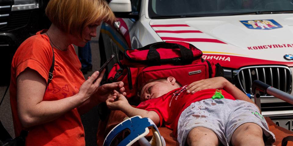 Eine Frau kümmert sich um ein Kind vor dem von russischen Raketen getroffenen Okhmatdyt-Kinderkrankenhaus.<span class="copyright">dpa</span>