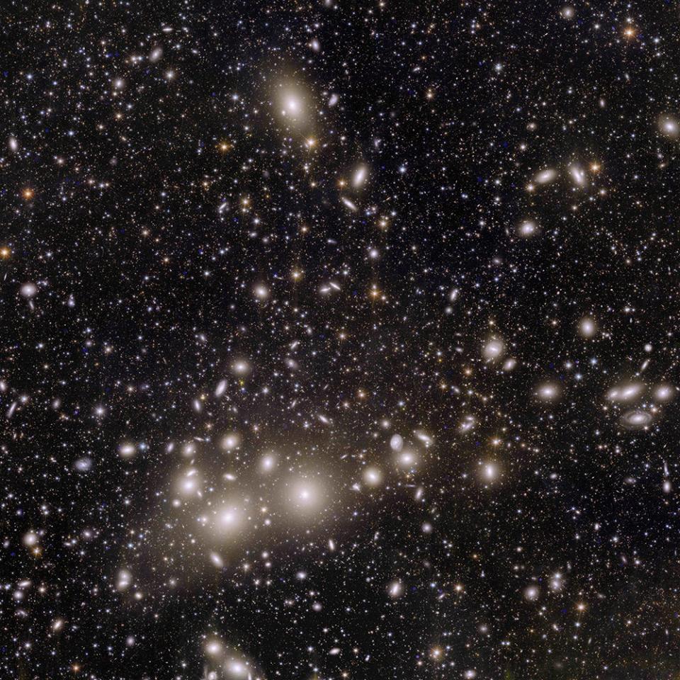 <em>This group picture of 1,000 galaxies in a cluster 240 million light-years away. It is positioned against a backdrop of over 100,000 galaxies that are billions of light-years away. A <u>light-year is 5.8 trillion miles</u>. Many of the faint galaxies in this image were previously unseen. Mapping out the distribution and shapes of these galaxies can help cosmologists determine more about how dark matter shaped our present universe over time. CREDIT: ESA/Euclid/Euclid Consortium/NASA, image processing by J.-C. Cuillandre (CEA Paris-Saclay), G. Anselmi</em>