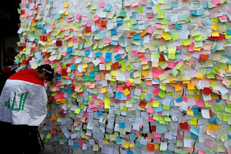 An Iraqi demonstrator pastes a note with his wish at a wall of wishes, during ongoing anti-government protests, at the building called 'the Turkish Restaurant Building', in Baghdad