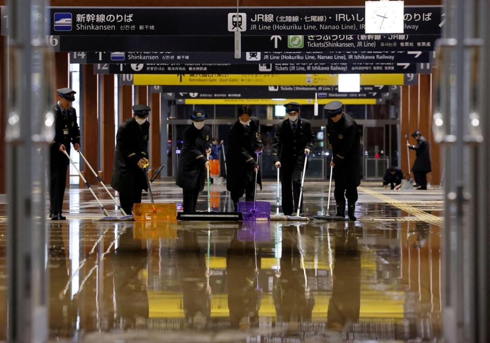 日本金澤車站人員1日強震過後清理車站地面。路透社