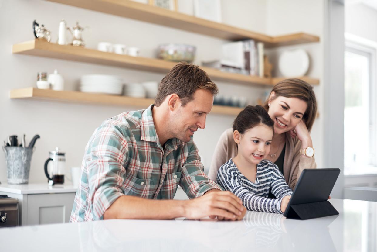 mother, father, and daughter in kitchen on tablet