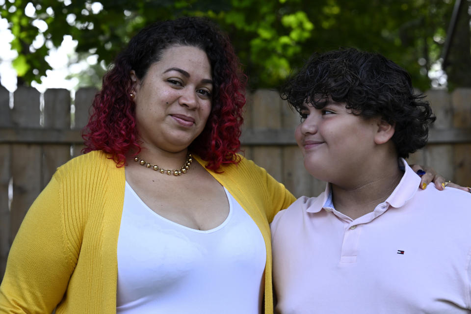 Rousmery Negrón stands with her son at home in Springfield, Mass., on Thursday, Aug. 3, 2023. When in-person school resumed after pandemic closures, Negrón and her son both noticed a change: School seemed less welcoming. Parents were no longer allowed in the building without an appointment, Negrón said. Punishments were more severe. Everyone seemed less tolerant, more angry. Negrón's son even overheard a teacher mocking his learning disabilities, calling him an ugly name. He would end up missing more than five months of sixth grade. (AP Photo/Jessica Hill)