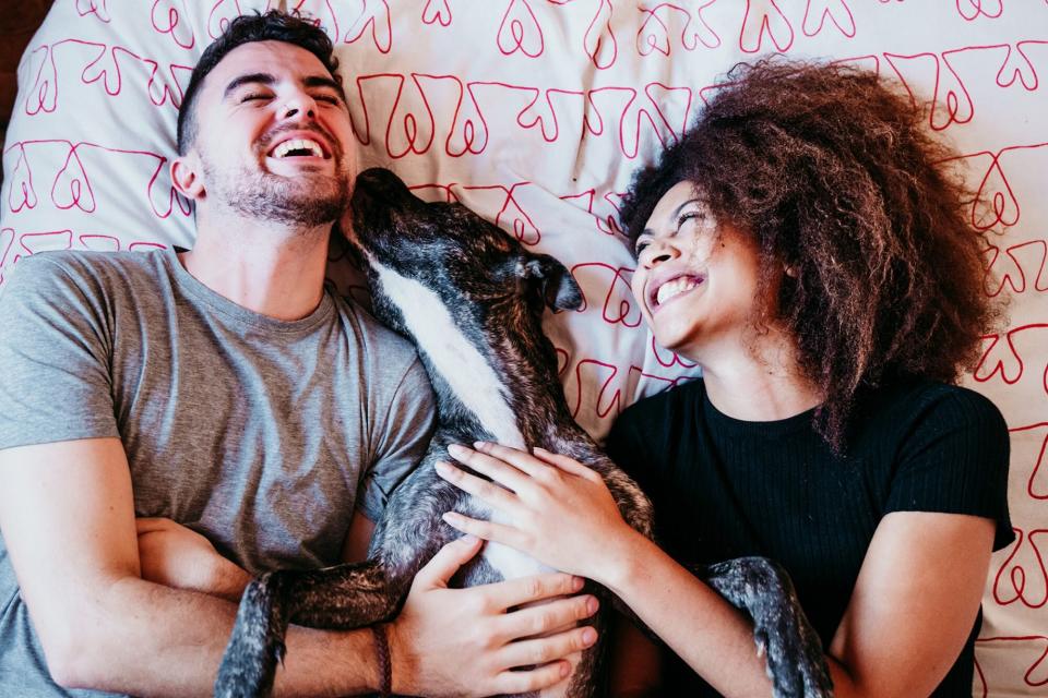 latinx couple holding dog and laughing