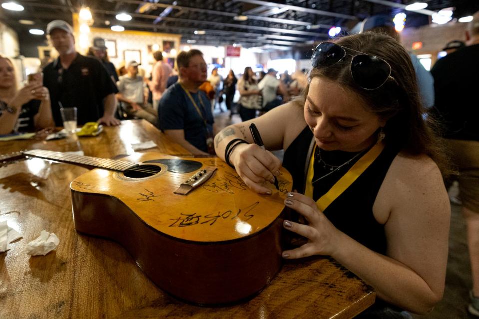 Bailey Gilbert signs a guitar after performing on the Salty Bronc Stage at the Bob Childers' Gypsy Cafe in Stillwater, Okla. on Sunday, May 7, 2023.