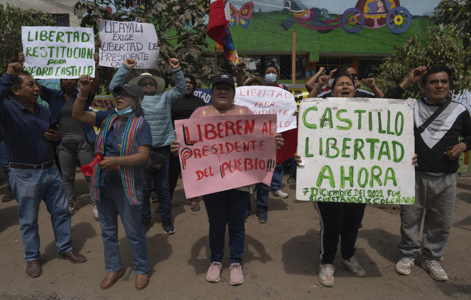 Supporters of ousted Peruvian President Pedro Castillo protest with signs in Spanish asking for Castillo to be freed, outside the National Police base where the former president is held for a hearing, facing charges of rebellion, on the outskirts of Lima, Peru, Tuesday, Dec. 13, 2022. Castillo was detained on Dec. 7 after he was ousted by lawmakers when he sought to dissolve Congress ahead of an impeachment vote. (AP Photo/Guadalupe Pardo)