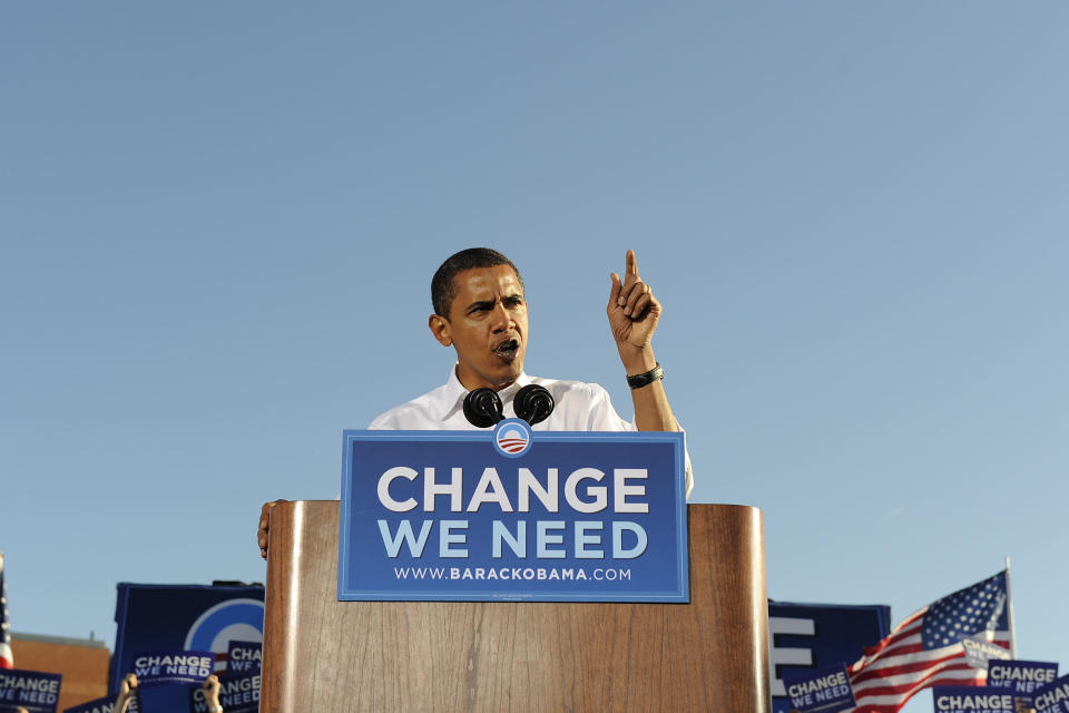 Barack Obama speaks during a rally for his first presidential campaign with a sign in front: Change We Need.