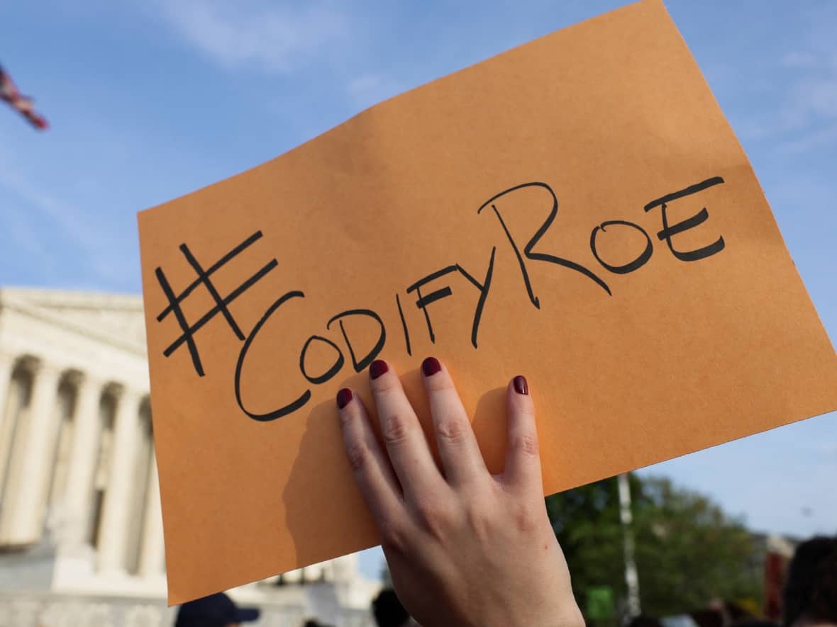 A demonstrator holds a sign during a protest outside the U.S. Supreme Court in Washington, D.C., on Tuesday, after the leak of a draft majority opinion suggested a majority of the court would overturn the landmark Roe v. Wade abortion rights ruling. (Evelyn Hockstein/Reuters - image credit)