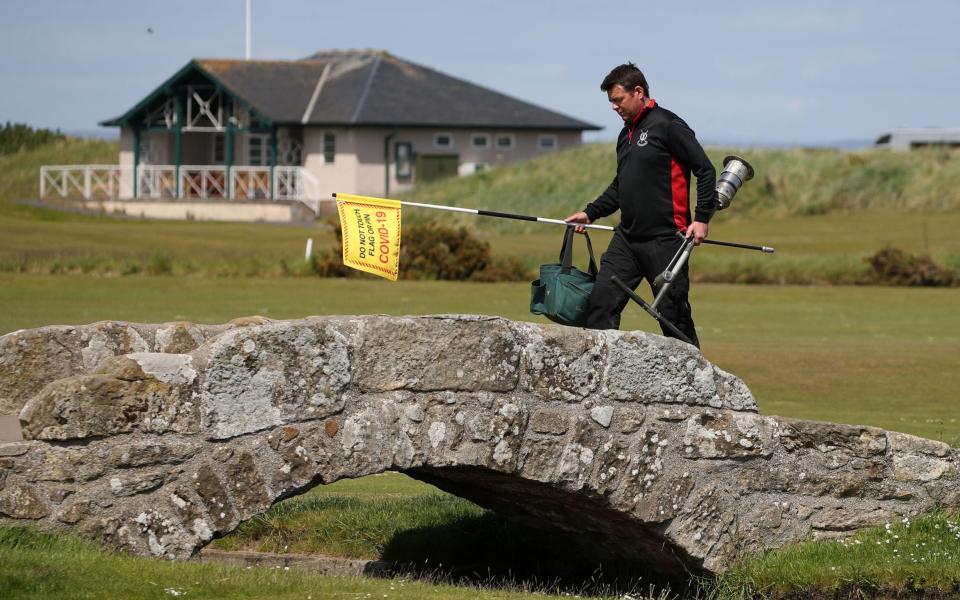 Greenkeeper Simon Connah crosses the Swilcan Bridge on the Old Course at St Andrews, in Fife as final preparations are completed to the course ahead of reopening - PA