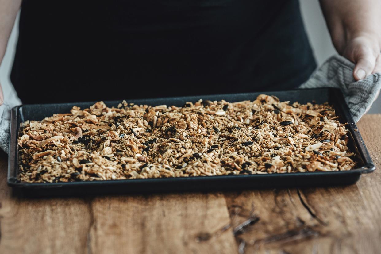 woman holding a baking tray with freshly baked homemade granola