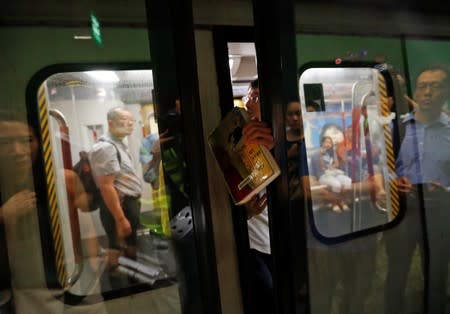 A protester uses his hand to prevent the doors of a Mass Transit Railway (MTR) subway train from closing during a disruption of MTR services at Fortress Hill station in Hong Kong