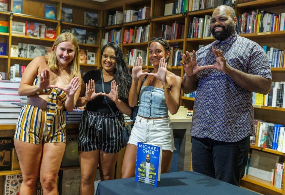 Author Michael Oher does the “U” with UM law students from left- Megan Nubauer, Sharmila Singh and Megan Williams after autographing his book titled “ When Your Back’s Against the Wall: Fame, Football, and Lessons Learned through a Lifetime of Adversity” for them at Books & Books in Coral Gables on Wednesday, August 23, 2023.