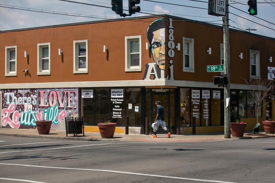 A man walks by the Ali Mural at 800 West Muhammed Ali Blvd in Louisville, KY.