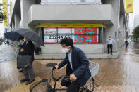 People wait for a traffic light, standing by screens showing Japan's Nikkei 225 index at a securities firm in Tokyo on Friday, Sept. 25, 2020. Asian shares advanced Friday, cheered by a modest rally on Wall Street and rising hopes for fresh stimulus for the U.S. economy. (AP Photo/Hiro Komae)