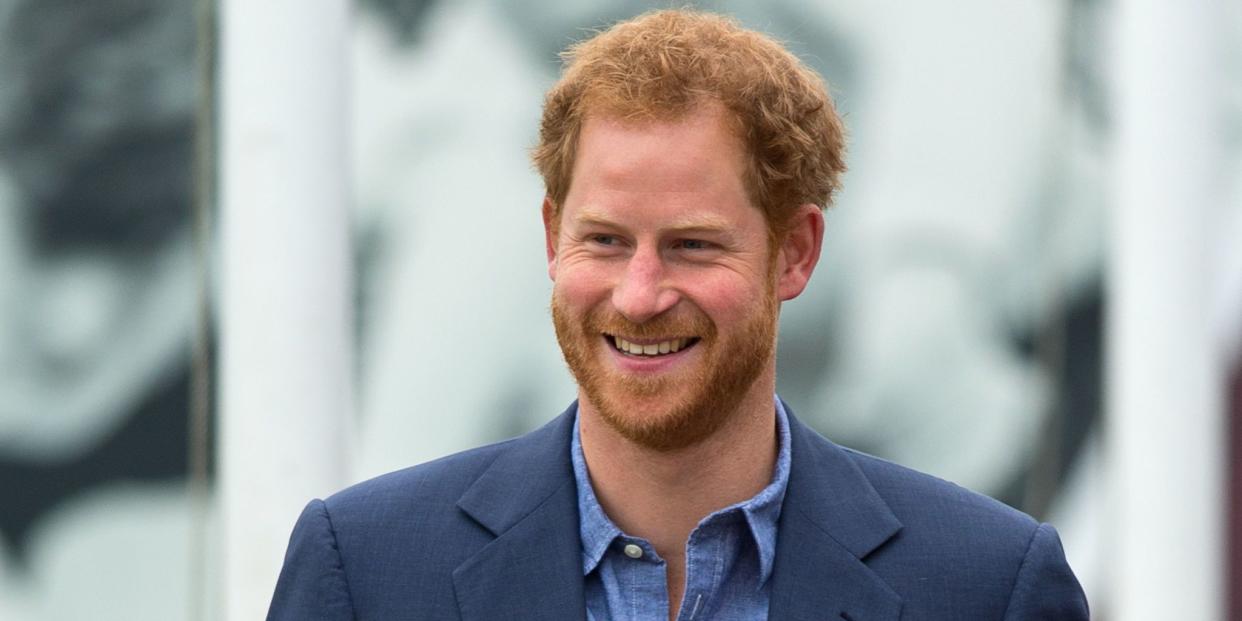 prince harry smiling whilst wearing a blue suit