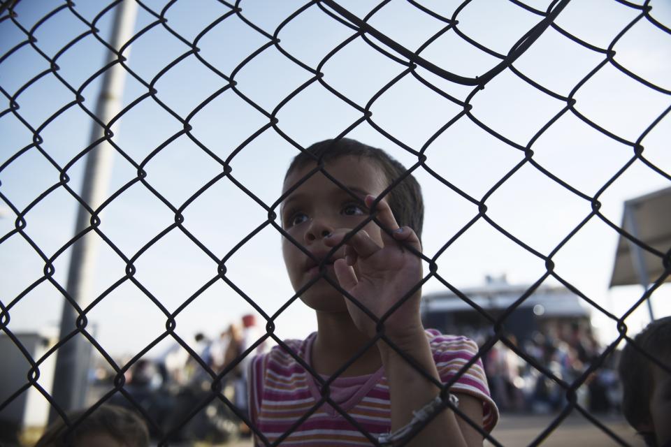 A migrant girl stands at the fence of the port of Thessaloniki, northern Greece, Monday, Sept. 2, 2019. About 1,500 asylum-seekers were being transported from Greece's eastern Aegean island of Lesbos to the mainland Monday as part of government efforts to tackle massive overcrowding in refugee camps and a recent spike in the number of people arriving from the nearby Turkish coast. (AP Photo/Giannis Papanikos)