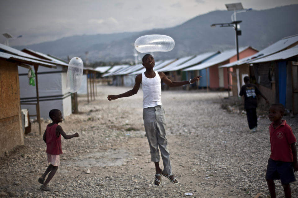 In this picture taken on Feb. 13, 2012, children play with blown-up condoms at La Piste camp in Port-au-Prince, Haiti.While more than a million people displaced by the 2010 quake ended up in post-apocalyptic-like tent cities, some of the homeless people with disabilities landed in the near-model community of La Piste, a settlement of plywood shelters along tidy gravel lanes. However, the rare respite for the estimated 500-plus people living at the camp is coming to an end as the government moves to reclaim the land. (AP Photo/Ramon Espinosa)