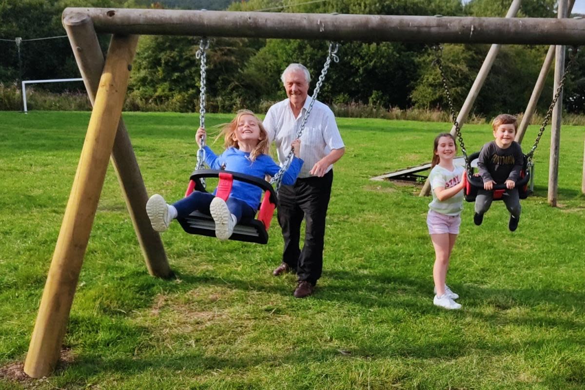 Councillor Steve Kay with (left to right) grandchildren Emily, Penelope and Thomas on the playing field at Charltons after swings were refurbished <i>(Image: LDR)</i>