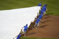 Grounds crew members cover the field as play is suspended due to rain during the eighth inning of a baseball game between the New York Mets and the Pittsburgh Pirates, Friday, July 9, 2021, in New York. (AP Photo/Frank Franklin II)