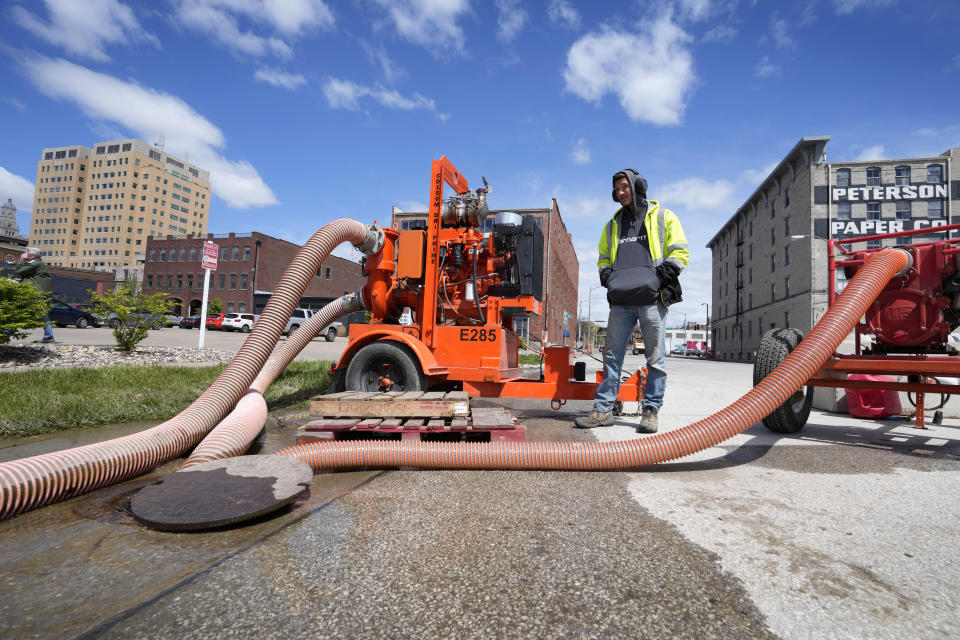 City worker Dylan Estlund monitors pumps near a sand filled flood barrier, Monday, May 1, 2023, in Davenport, Iowa. (AP Photo/Charlie Neibergall)