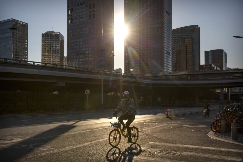 Un hombre con mascarilla viaja en bicicleta por una calle casi vacía en Beijing, el sábado 22 de febrero de 2020. China informó el sábado que el conteo diario de casos del nuevo virus en el país cayó significativamente a 397, aunque otras 109 personas murieron de COVID-19, la enfermedad causada por el virus. (Foto AP / Mark Schiefelbein)