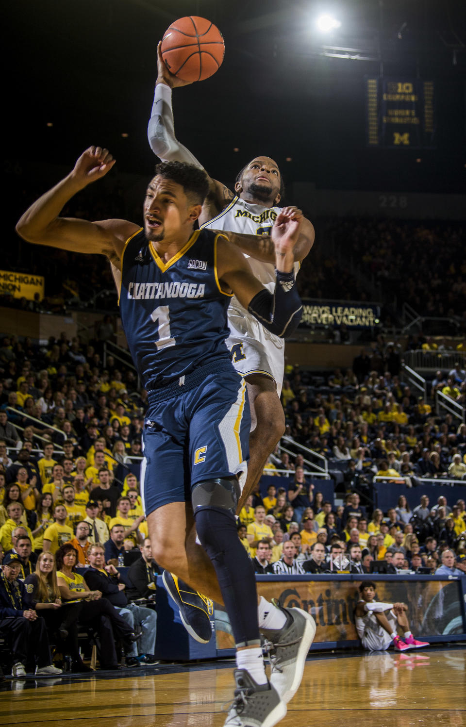 Michigan guard Zavier Simpson, top, attempts to make a basket over Chattanooga guard Jonathan Scott (1), in the second half of an NCAA college basketball game at Crisler Center in Ann Arbor, Mich., Friday, Nov. 23, 2018. (AP Photo/Tony Ding)