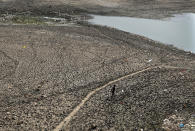 A man walks across a dried patch of the river Yamuna as water level reduces drastically following heat wave to in New Delhi, Monday, May 2, 2022. The intense heat wave sweeping through South Asia was made more likely due to climate change and it is a sign of things to come. An analysis by international scientists said that this heat wave was made 30-times more likely because of climate change, and future warming would make heat waves more common and hotter in the future. (AP Photo/Manish Swarup)