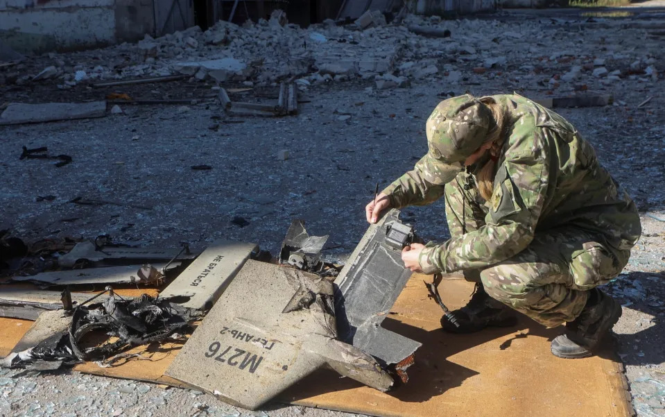 A Ukrainian soldier examines what is thought to be an Iranian Kamikaze drone at the site of a Russian strike - STRINGER