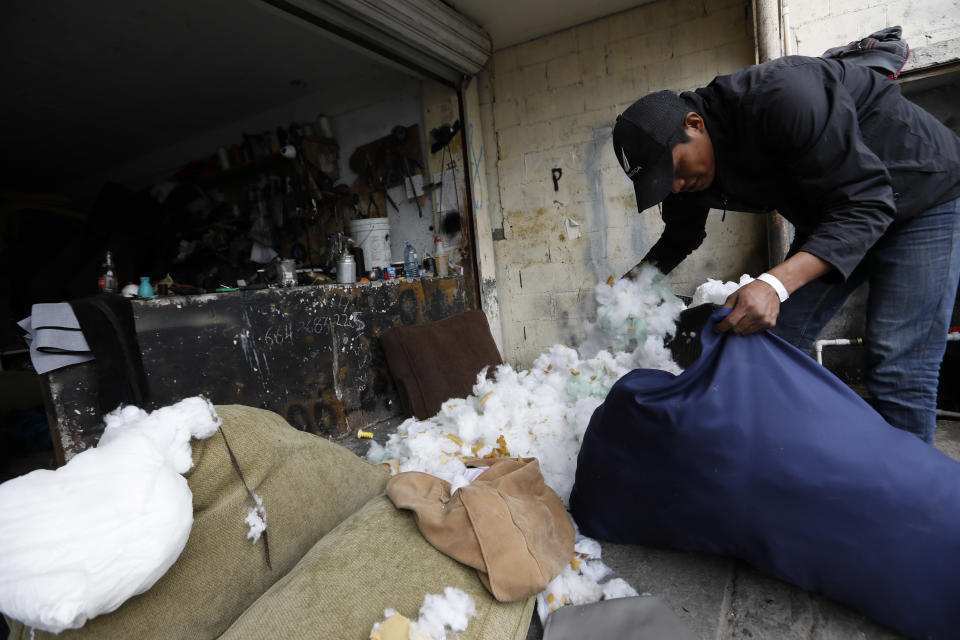 In this Dec. 5, 2018 photo, Honduran migrant Jose Perez, 22, stuffs a pillow as he works as a day laborer at an upholstery shop in Tijuana, Mexico. Mexican authorities have encouraged all of the migrants to regularize their status in Mexico and seek work. (AP Photo/Rebecca Blackwell)