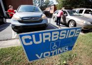 Election officials help voters with disabilities cast their ballots from their cars at a polling station as early voting for the 2016 general elections begins in North Carolina, in Carrboro, North Carolina, U.S., October 20, 2016. REUTERS/Jonathan Drake