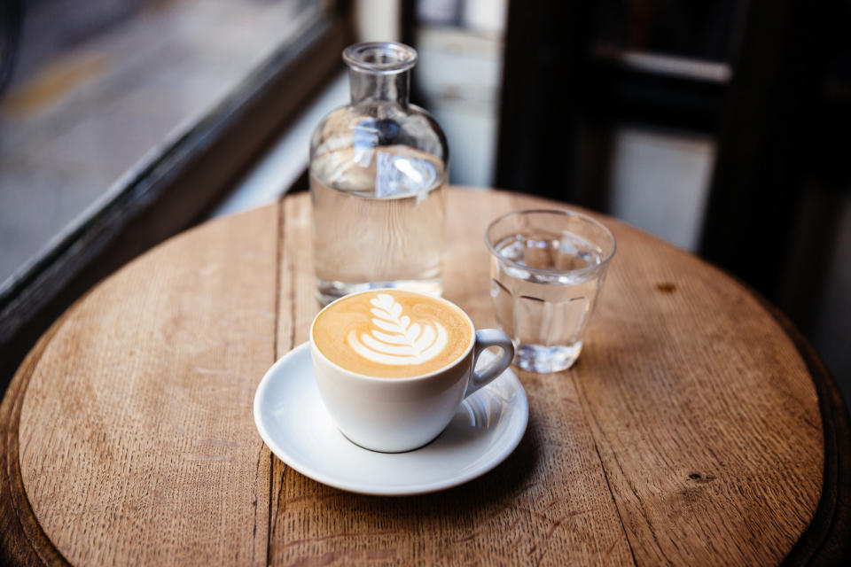 A cappuccino and a glass of water on a table