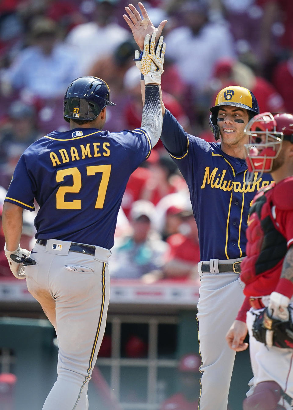 Milwaukee Brewers' Willy Adames (27) celebrates with Christian Yelich after hitting a home run during the ninth inning of the team's baseball game against the Cincinnati Reds in Cincinnati, Sunday, July 18, 2021. (AP Photo/Bryan Woolston)