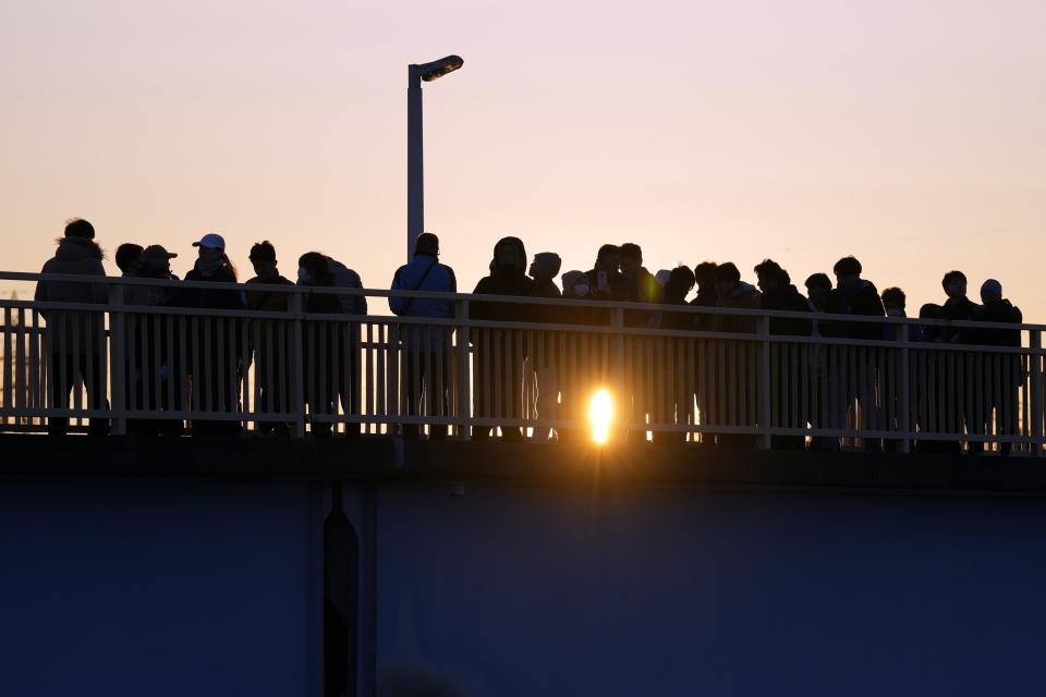 Un grupo de personas observa el primer amanecer del Año Nuevo desde un puente peatonal, el lunes 1 de enero de 2024, en Yokohama cerca de Tokio. (AP Foto/Eugene Hoshiko)