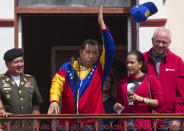 El presidente Hugo Chávez lanza la gorra del equipo de béisbol de Magallanes a sus seguidores, en un balcón del palacio de Miraflores, en Caracas, Venezuela, el 17 de marzo de 2012, un día después de su llegada de Cuba. AP Photo/Ariana Cubillos