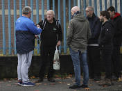 In this image taken on Tuesday, Oct. 15, 2019 former IRA member Jack Duffin, second left, hands over the role of tour guide to an unidentified Loyalist, left, from Belfast Political Tours, which takes tourists on a tour of both sides of the sectarian divide in west Belfast, Northern Ireland. (AP Photo/Peter Morrison)