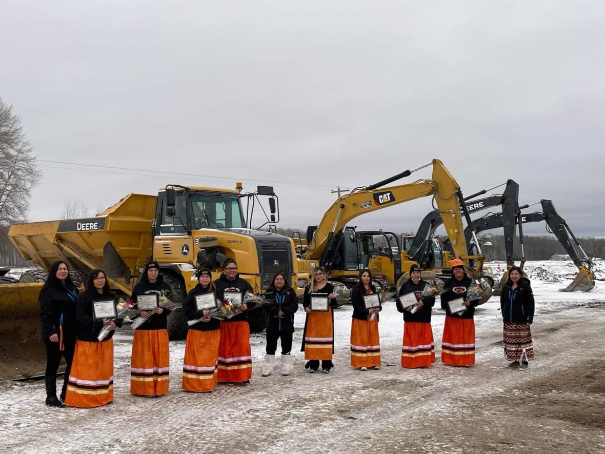 Some of the graduates and community staff members. The women wore traditional ribbon skirts as part of their celebration.  ( Interior Heavy Equipment Operator School - image credit)