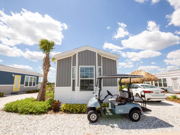 A cabana with a golf cart. Both next to a car.