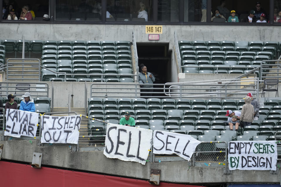 Fans sit behind signs hanging in right field at RingCentral Coliseum during a baseball game between the Oakland Athletics and the Houston Astros in Oakland, Calif., Sunday, May 28, 2023. (AP Photo/Jeff Chiu)