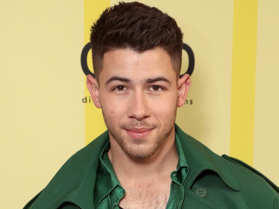 Nick Jonas in a green jacket on the red carpet.