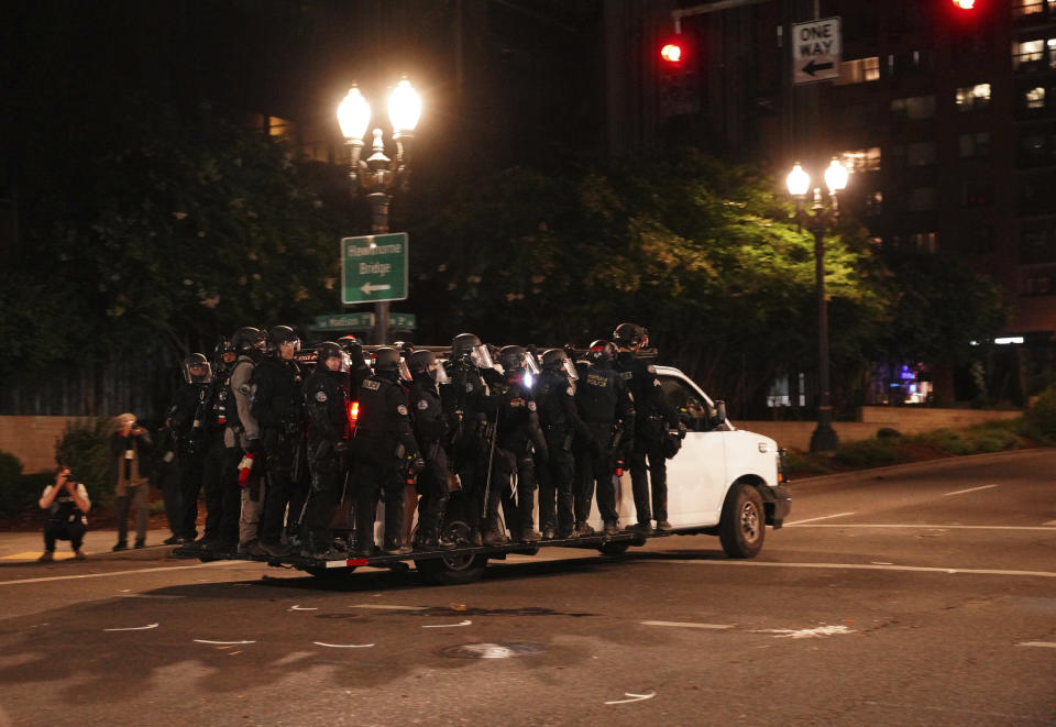 Portland Police line around a van and drive away from protesters rallying at the Mark O. Hatfield United States Courthouse on Saturday, Sept. 26, 2020, in Portland, Ore. (AP Photo/Allison Dinner)