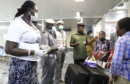 Nigerian custom officers wearing face masks and gloves screen passengers arriving at Nnamdi Azikiwe International Airport in Abuja August 11, 2014. REUTERS/Afolabi Sotunde