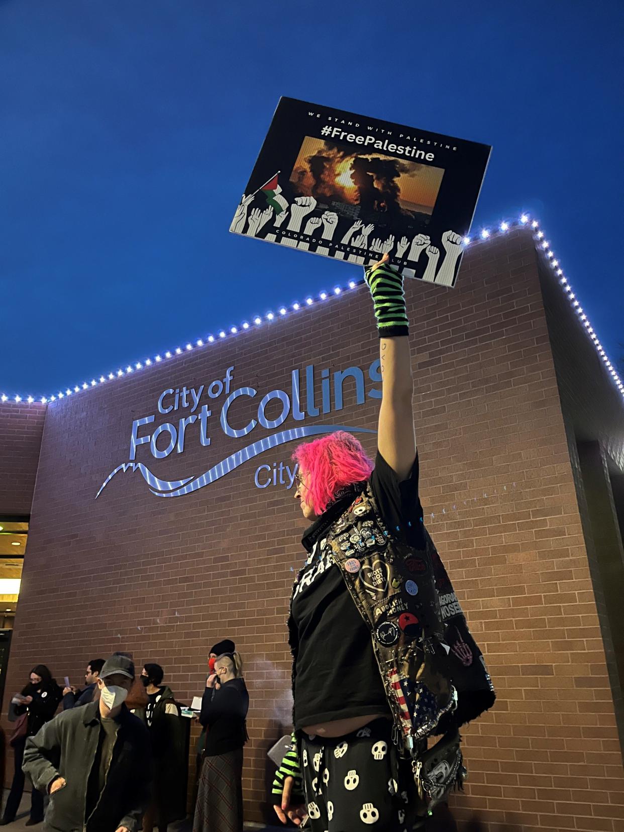 A person holds up a sign that says "Free Palestine" outside Fort Collins City Hall on Tuesday. At least 100 people showed up to urge council to pursue and pass a resolution supporting a cease-fire in Gaza.