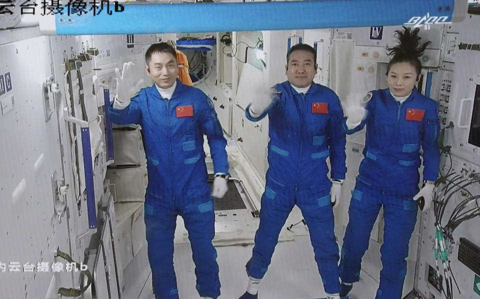 FILE - In this photo released by Xinhua News Agency, screen image captured at Beijing Aerospace Control Center in Beijing, China on Oct. 16, 2021, shows three Chinese astronauts, from left, Ye Guangfu, Zhai Zhigang and Wang Yaping waving after entering the space station core module Tianhe. Three Chinese astronauts returned to Earth on Saturday, April 16, 2022, after six months aboard China's newest space station in the longest crewed mission to date for its ambitious space program. (Tian Dingyu/Xinhua via AP, File)