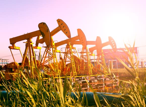 Several pumpjacks in a row with sunburst