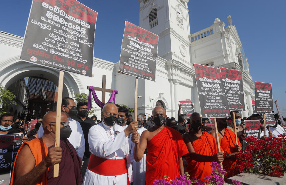 Cardinal Malcolm Ranjith, archbishop of Colombo, second left, along with Buddhist monks and other Catholic devotees hold placards during a protest demanding justice for the 2019 Easter Sunday bomb attack victims out side the St. Anthony's church, one of attack sites, in Colombo, Sri Lanka, Sunday, March 7, 2021. Placards read, “Easter Sunday Massacre, Who ran the operation behind the curtain” (AP Photo/Eranga Jayawardena)