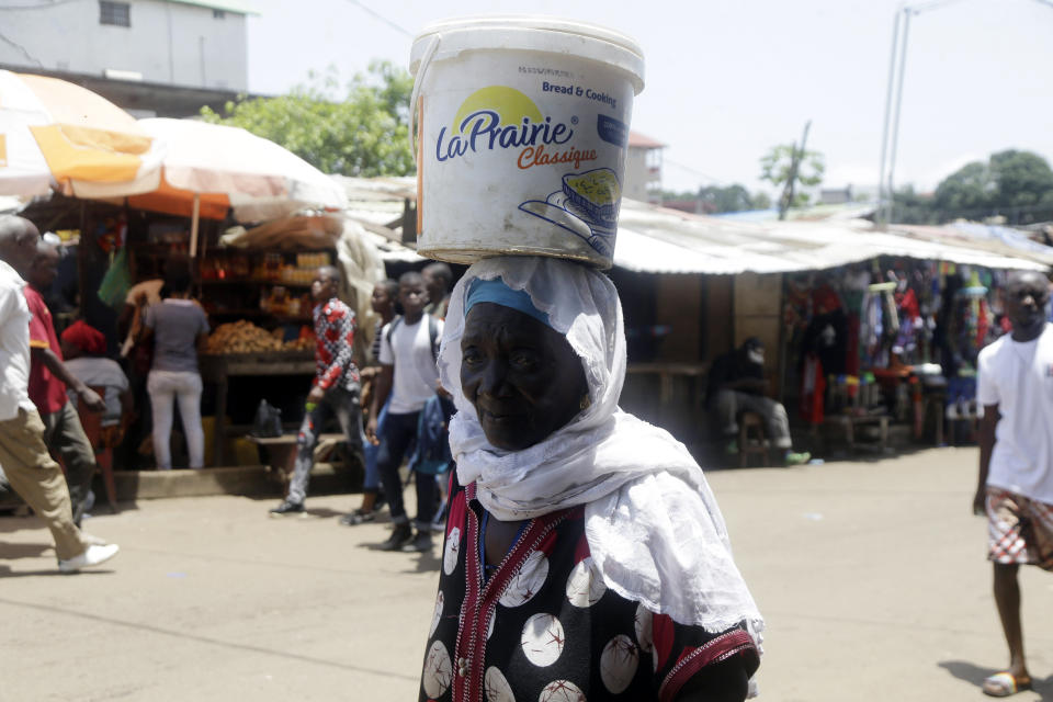 A woman balance a bucket in a local market in Conakry, Guinea, Thursday, Sept. 9, 2021. Guinea's new military leaders sought to tighten their grip on power after overthrowing President Alpha Conde, warning local officials that refusing to appear at a meeting convened Monday would be considered an act of rebellion against the junta. (AP Photo/ Sunday Alamba)