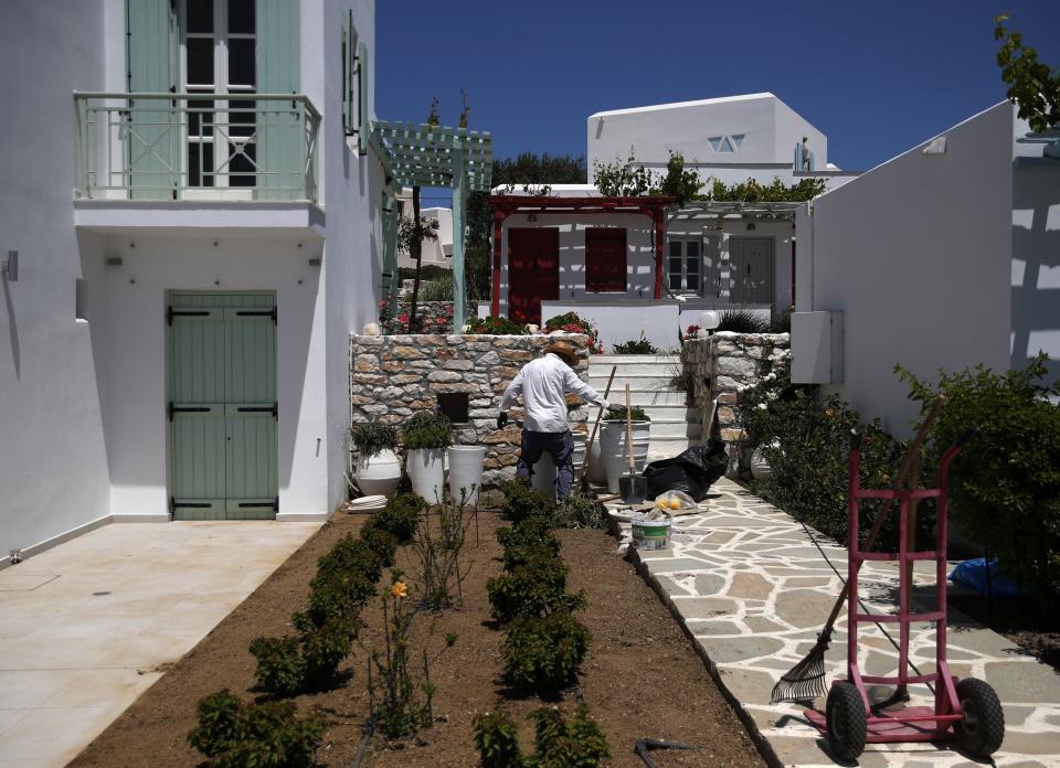 A man cleans the garden of a hotel in Agios Prokopios village, on the Aegean island of Naxos, Greece, Wednesday, May 12, 2021. (AP Photo/Thanassis Stavrakis)