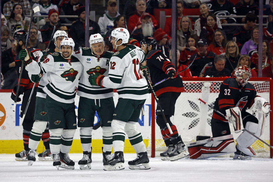 Minnesota Wild's Kirill Kaprizov, center, celebrates with teammates Mats Zuccarello, left, and Matt Boldy (12) in front of Carolina Hurricanes' Jaccob Slavin (74) and goaltender Antti Raanta (32) after his second goal of an NHL hockey game, during the second period in Raleigh, N.C., Sunday, Jan. 21, 2024. (AP Photo/Karl B DeBlaker)